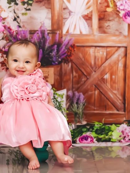 Another delightful shot from the floral-themed sitter session. The baby's happy expression and cute pose make this a truly heartwarming photograph.