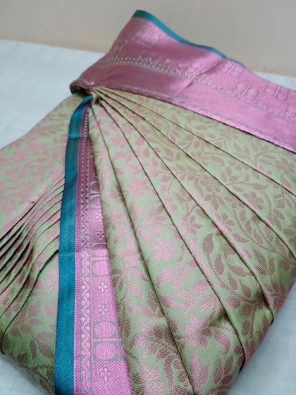 The pleats on this light green and pink saree have been customized based on the client's physique for the most flattering fit.