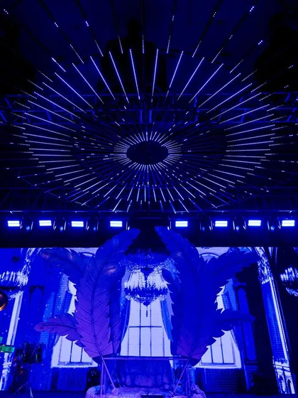 A futuristic Sangeet stage with a massive LED screen backdrop and large, feather-like set pieces, creating a dynamic and visually stunning setting for performances.