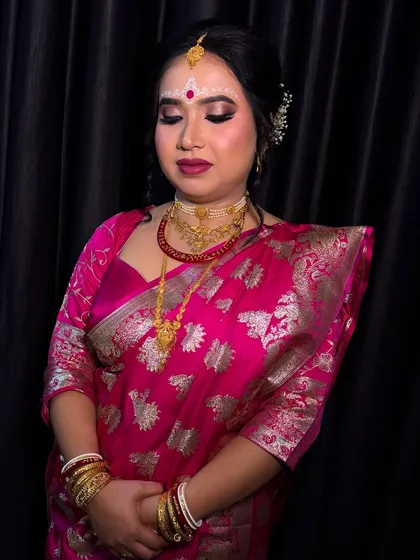 A full look of the Bengali bride without her veil and mukut, showing the beautiful hairstyle and the elegant drape of the saree.