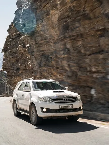 Using a panning technique to create motion blur, I captured this white Toyota Fortuner driving along a winding mountain pass. This type of rolling shot adds a dynamic, in-the-moment feel to an automotive photoshoot, emphasizing the vehicle's movement.