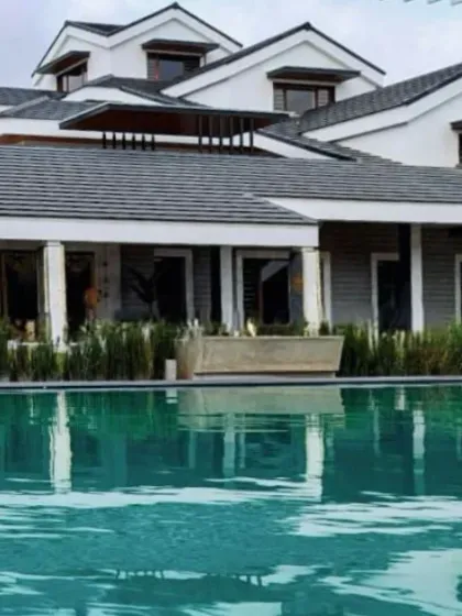 Reflections of sophistication. A classic farmhouse design is beautifully mirrored in the calm waters of the adjacent pool, blending architecture, water, and sky.