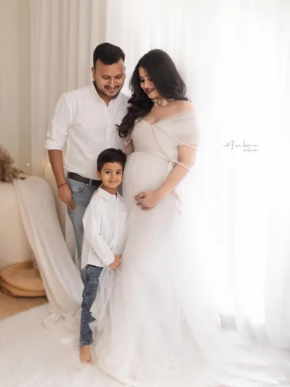 A heartwarming family portrait, with their son joining them. It’s a beautiful capture of a family excited to welcome their newest member, all styled in coordinating light colors.