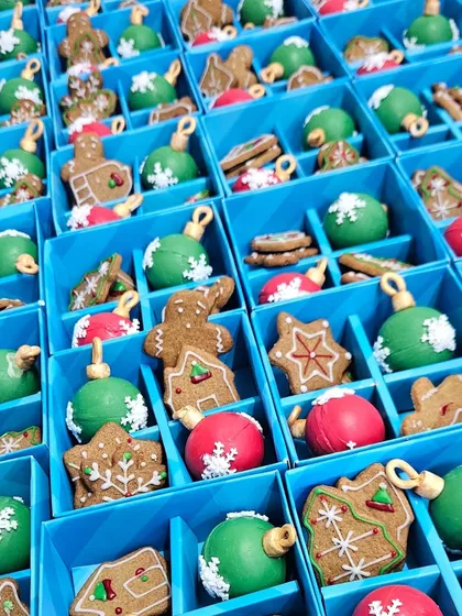 An overhead shot of our Christmas assortment boxes being filled with gingerbread cookies and colorful chocolate bombs. It's a sight of pure holiday cheer!