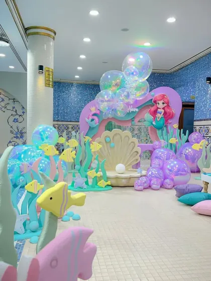 This wide shot shows how we transformed a poolside area into a complete mermaid kingdom, with themed props and low seating for the kids.