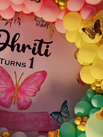 A close-up of a butterfly-themed first birthday backdrop. The soft pink and gold color palette and delicate butterfly graphics create a sweet and elegant look.