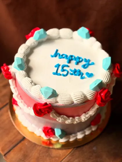 A colorful cake for a 15th birthday, decorated with buttercream gems and roses.