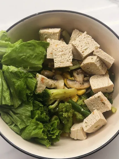 A bowl of sautéed vegetables with tofu, broccoli, and mushrooms, served with fresh lettuce. A perfect meal for a metabolism boost.