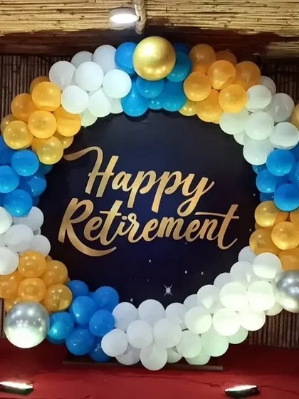 A cheerful setup for a retirement party. I designed a circular backdrop with a 'Happy Retirement' message, framed by a balloon garland in blue, yellow, and white.