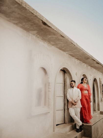 A wide-angle shot showcasing the couple against a minimalist building with repeating arches. The clean lines and open space give this portrait a contemporary and stylish feel.