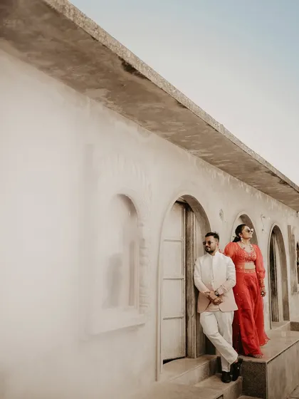 A stylish, editorial-style portrait using the venue's architecture. The couple poses against a rustic wall, creating a modern and fashionable look.
