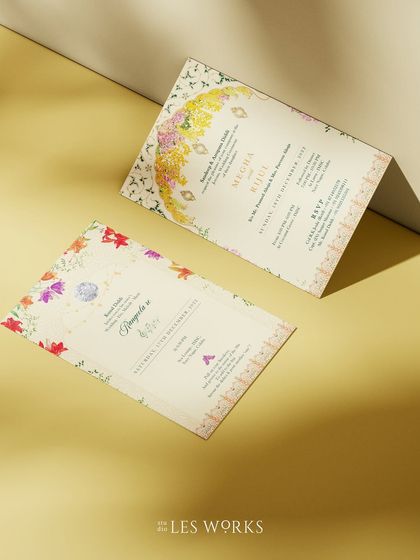 A set of minimal floral invitations with a touch of Indian inspiration. The design uses a soft color palette and delicate watercolor flowers arranged in the shape of a traditional arch.