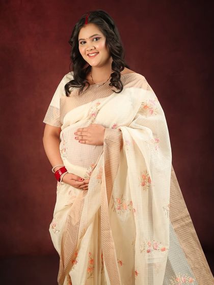 A bright and happy portrait of an expecting mother in a traditional saree. Her direct gaze and gentle smile radiate confidence and joy.