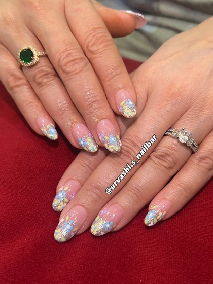 A dreamy, feminine design with delicate 3D-style pastel blossoms. The flowers are set against a shimmery, soft gradient base, giving the manicure a gentle yet luxurious feel perfect for spring.