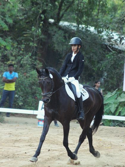 A young rider dressed in formal competition attire during the Auroville Horse Show, showcasing the discipline and presentation required in equestrian sports.
