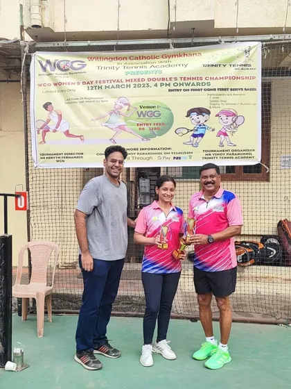 Another winning pair from the Mixed Doubles event proudly displaying their trophies in front of the official event banner.