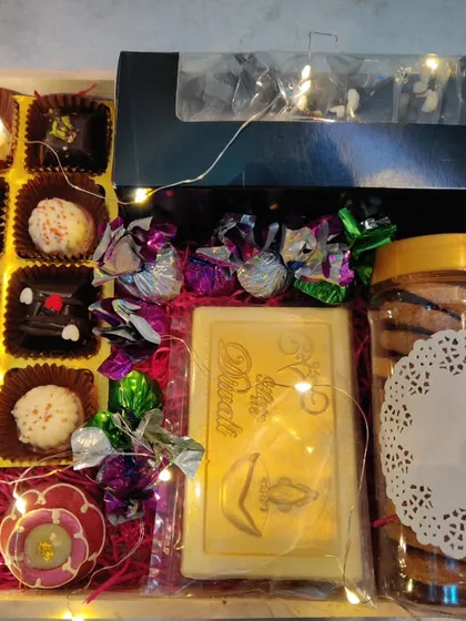 The contents of the hamper revealed: a box of truffles, a chocolate bar, cookies, and handmade diyas, all nestled with fairy lights.