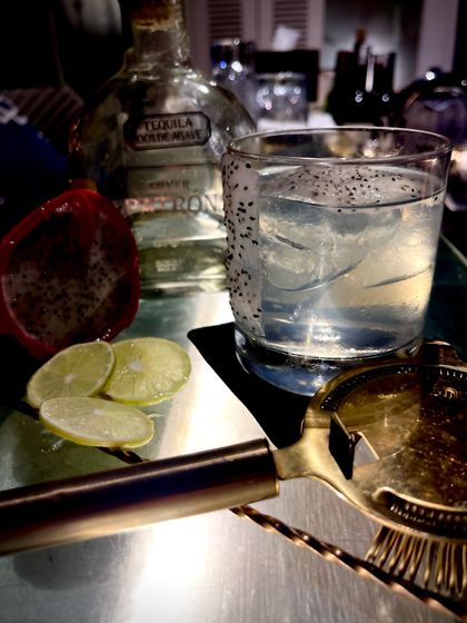 The Jelisco Dragon, one of our signature cocktails. This refreshing drink features tequila, dragon fruit seeds, and fresh lime, perfect for a summer evening.