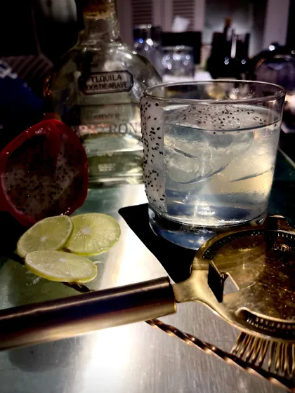 The Jelisco Dragon, a unique cocktail featuring tequila and dragon fruit seeds, served over ice for a refreshing and exotic taste.
