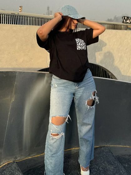 Adjusting the denim cap, a key accessory for this street style outfit.