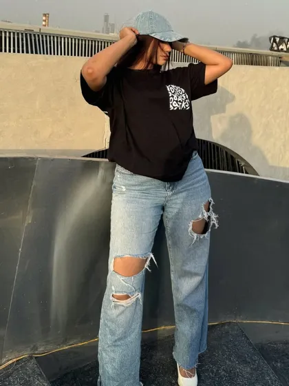 Adjusting the denim cap, a key accessory for this street style outfit.