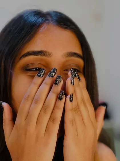 A playful pose with the black glitter nails, showing how a great manicure can boost confidence.