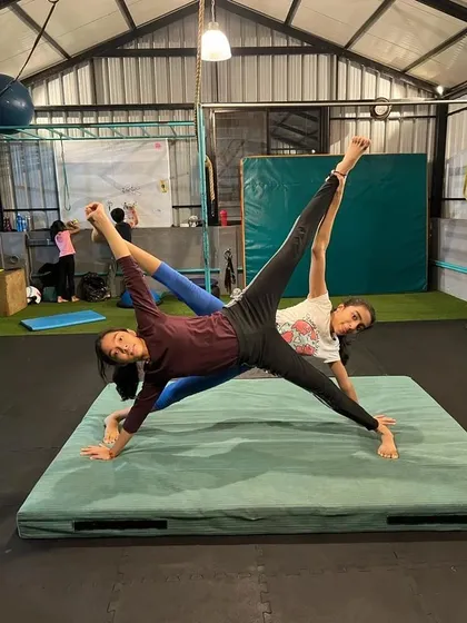 Two students working together on a synchronized side plank with a leg lift. This partner drill is great for building core strength and stability.