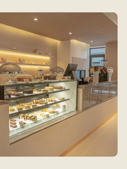 A close-up of our brightly lit pastry counter, showcasing the variety of cakes and desserts we offer daily.