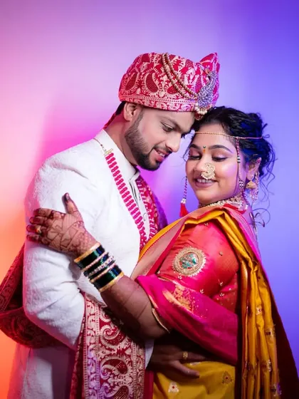 A tender moment of embrace. The colorful lighting and the couple's traditional outfits create a unique and beautiful wedding portrait.