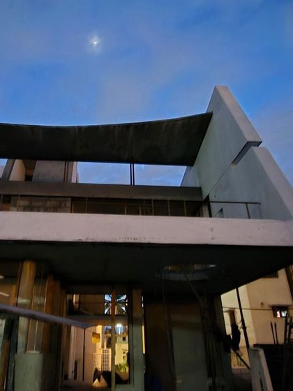The 'House of Sia' seen at twilight during its construction. The sculptural concrete forms and curved roof begin to define their presence against the evening sky, hinting at the unique home to come.