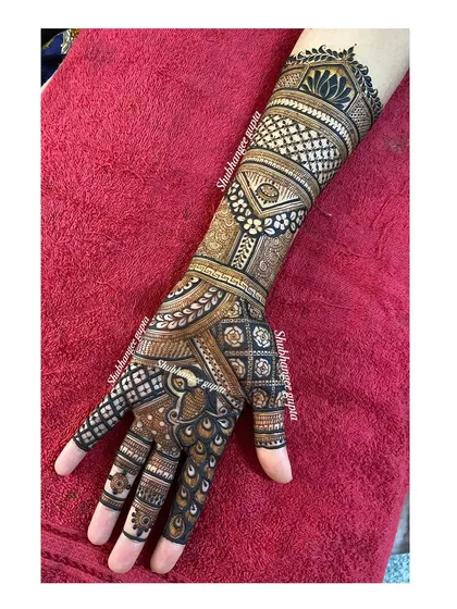 A traditional mehndi design that covers the entire hand and forearm. I used a mix of checks, floral patterns, and a central peacock motif to create a classic and timeless look.