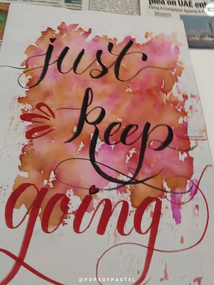 A finished piece from our workshop, showcasing beautiful brush lettering with a vibrant watercolor background.