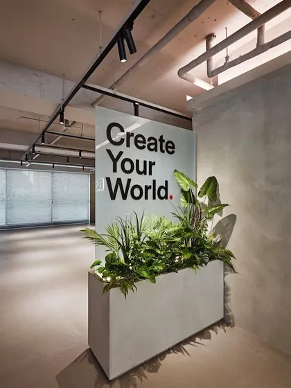 A simple, modern planter at the entrance of an office space. Paired with the motivational "Create Your World" sign, the greenery reinforces a message of growth and potential.