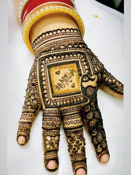 A close-up of the finished personalized design, featuring the hashtag '#Mitila'. The surrounding patterns of peacocks and detailed linework make the hashtag a central design element.