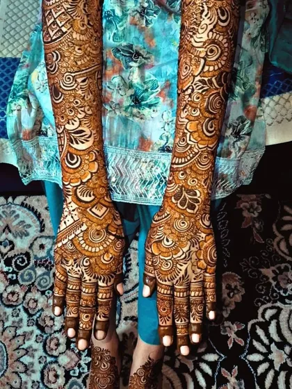 A full view of this stunning bridal henna, showing the design from the fingertips all the way to the elbows. The patterns are dense and detailed, perfect for a traditional bridal look.