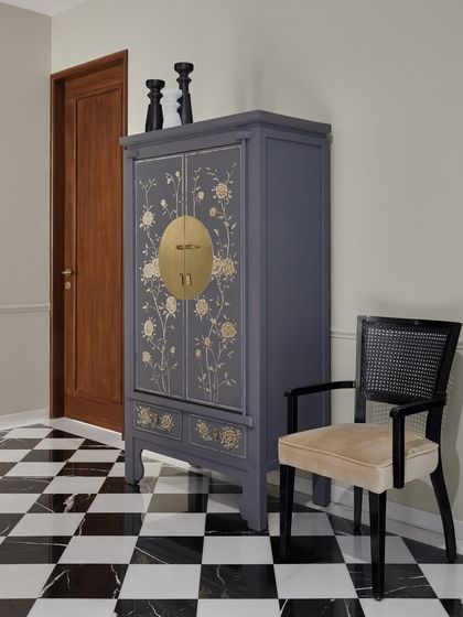 In this Worli residence, I used my favorite black and white checkered flooring to create a classic foyer. Instead of a typical console, I sourced a stunning grey oriental wedding cabinet that cleverly houses a coffee and snack station for the family.