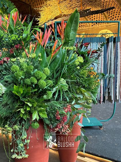 A large, vibrant floral arrangement in terracotta pots, created for a home decor brand event.