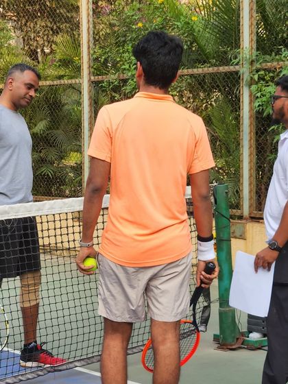 A coach and players review plans on the tennis court. Our programs are built on a foundation of clear instruction, dedicated practice, and strategic gameplay.