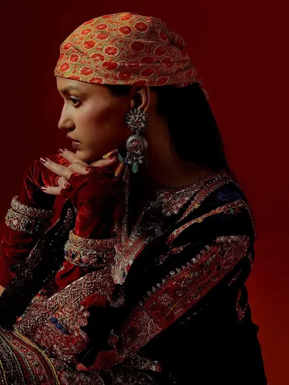 An artistic, moody shot for Debyani & Co, with the model posed against a rich, red-painted set wall.
