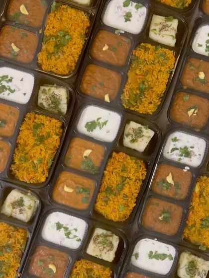 An overhead shot of the meal boxes, showing the delicious Tawa Pulao, Pav Bhaji, and other items packed inside.