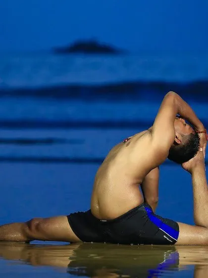 Just by breaking our own mental and physical barriers, we become flexible. This advanced pose on the wet sands of Gokarna beach at twilight reflects the deep flexibility of mind and body that yoga can cultivate.