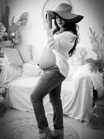 A chic and casual black and white portrait. The mom-to-be, wearing jeans and a white shirt, looks stylish and confident in this modern take on maternity photography.