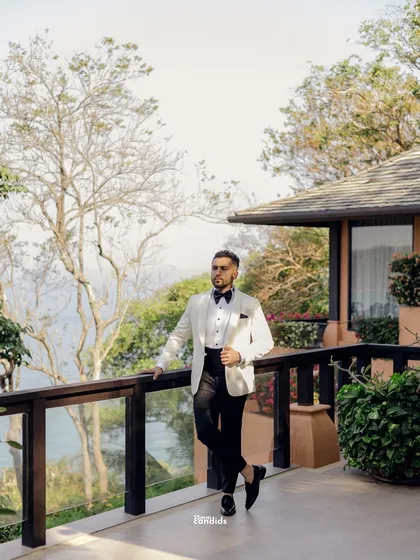 The groom, looking dapper in his white tuxedo, takes a moment before the evening reception. A classic portrait against the beautiful backdrop of the Thai resort.