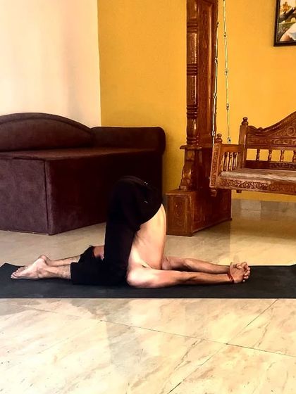 Karnapidasana (Knee-to-Ear Pose), an intense forward-bending inversion that calms the nervous system.