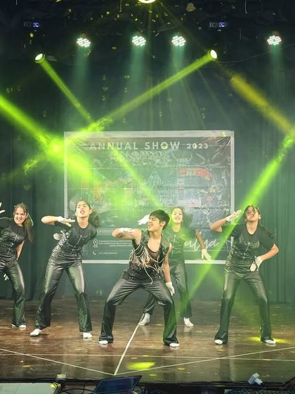 The dancers strike a fierce pose under green spotlights, capturing the energy of their performance.