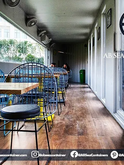 This cozy seating area within the cafe demonstrates efficient space planning. Large windows provide ample natural light and views of the surrounding landscape, making the narrow container feel open and airy.