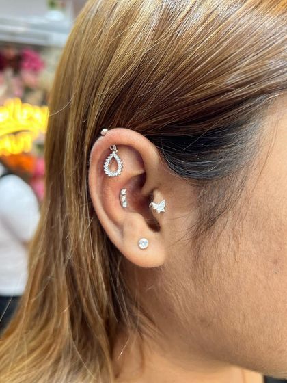 This stack combines a teardrop hanging, a three-stone stud, and a small butterfly for a nature-inspired look.