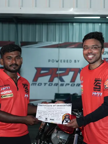 The reward for dedication. A student proudly receives his Certificate of Graduation after completing our intensive two-day track school program.