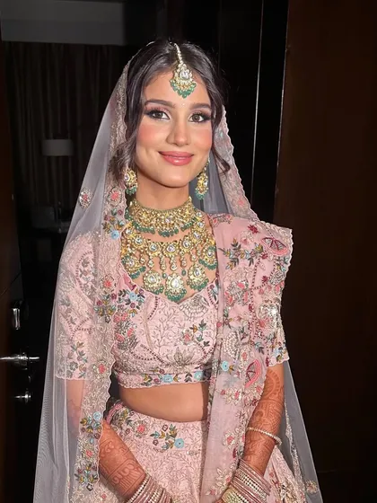 A beautiful summer bride ready for her sundowner wedding. The makeup is soft and pretty, with pink tones on the eyes and cheeks to complement her pastel floral lehenga by Anamika Khanna.