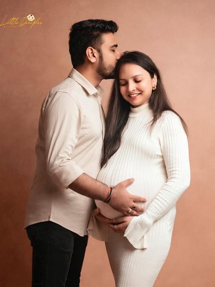 A sweet kiss on the forehead, a simple gesture of love captured beautifully in this minimalist studio maternity portrait.
